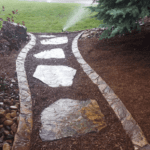Stone path leading to lawn being watered